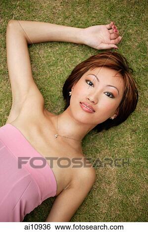 Young woman, lying on grass, looking at camera View Large Photo Image Stock Photograph - Young woman, lying on grass, looking at camera. Fotosearch