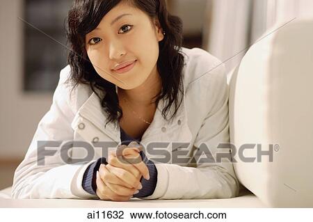Young woman, lying on sofa, looking at camera View Large Photo Image Stock Image - Young woman, lying on sofa, looking at camera. Fotosearch