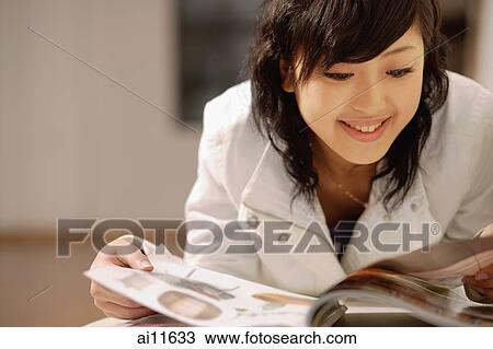 Young woman, lying on sofa, looking at magazine View Large Photo Image Stock Image - Young woman, lying on sofa, looking at magazine. Fotosearch