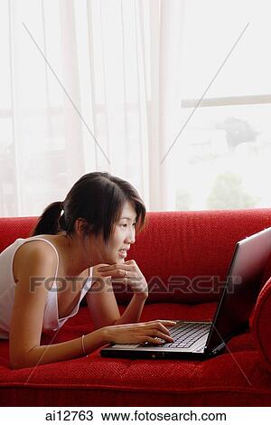 Young woman, lying on sofa, using laptop View Large Photo Image Stock Image - Young woman, lying on sofa, using laptop. Fotosearch