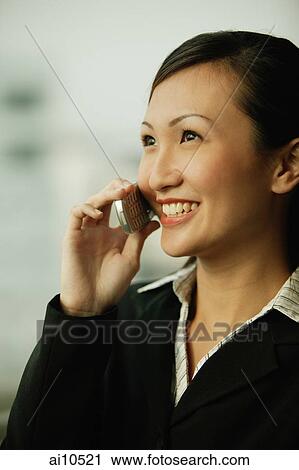 Stock Image - Young woman on mobile phone, smiling. Fotosearch