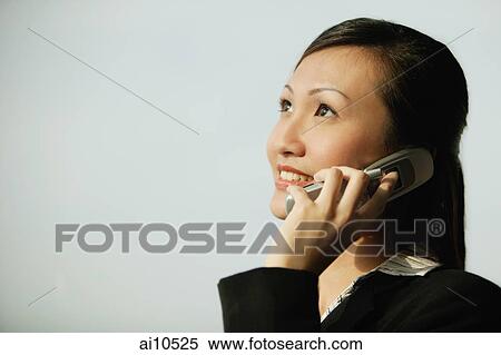 Young woman on mobile phone, smiling, looking up View Large Photo Image Stock Photography - Young woman on mobile phone, smiling, looking up. Fotosearch