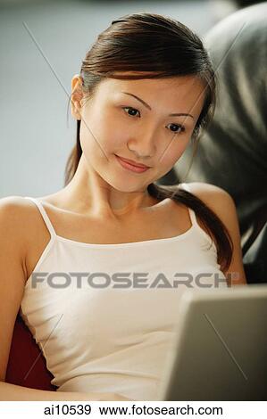 Young woman on sofa, using laptop, smiling View Large Photo Image Stock Photo - Young woman on sofa, using laptop, smiling. Fotosearch