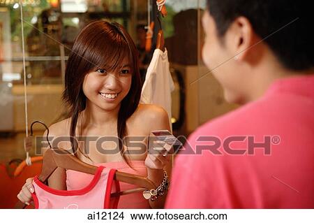 Young woman passing store clerk her credit card View Large Photo Image Picture - Young woman passing store clerk her credit card. Fotosearch