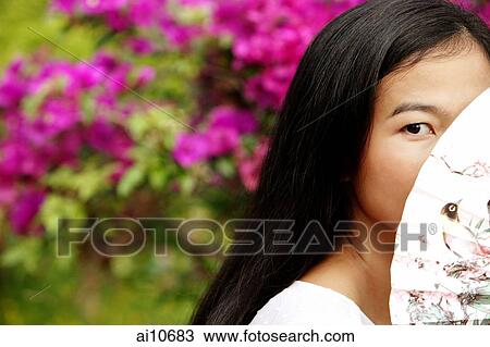 Young woman peeking behind a fan. View Large Photo Image Stock Image - Young woman peeking behind a fan.. Fotosearch