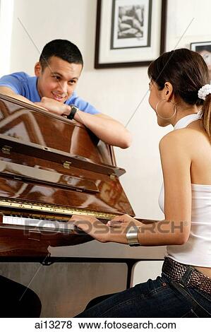 Young woman playing the piano, young man leaning on arms, smiling at her View Large Photo Image Stock Photo - Young woman playing the piano, young man leaning on arms, smiling at her. Fotosearch