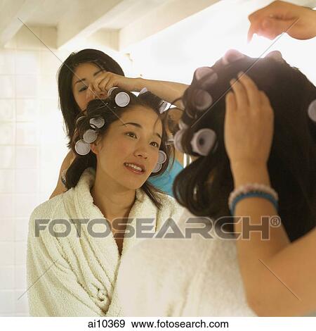 Young woman putting curlers in another woman's hair View Large Photo Image Stock Photo - Young woman putting curlers in another woman's hair. Fotosearch
