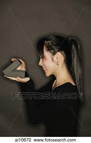 Young woman, side view, opening a box, black background View Large Photo Image Stock Image - Young woman, side view, opening a box, black background. Fotosearch