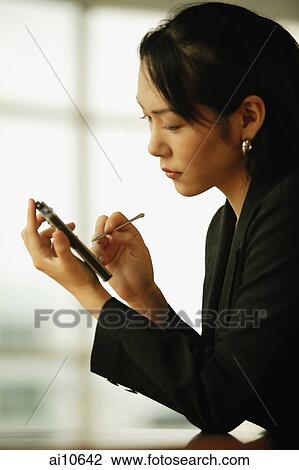 Young woman sitting at desk, using PDA View Large Photo Image Stock Image - Young woman sitting at desk, using PDA. Fotosearch