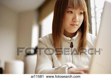 Young woman sitting at table using laptop View Large Photo Image Stock Image - Young woman sitting at table using laptop. Fotosearch