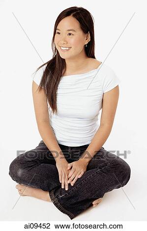 Young woman sitting cross-legged, looking off camera. View Large Photo Image Stock Image - Young woman sitting cross-legged, looking off camera.. Fotosearch