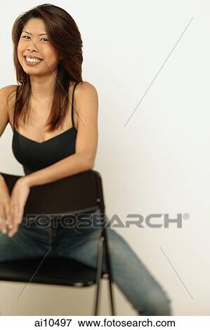 Young woman sitting down, looking at camera View Large Photo Image Stock Photo - Young woman sitting down, looking at camera. Fotosearch