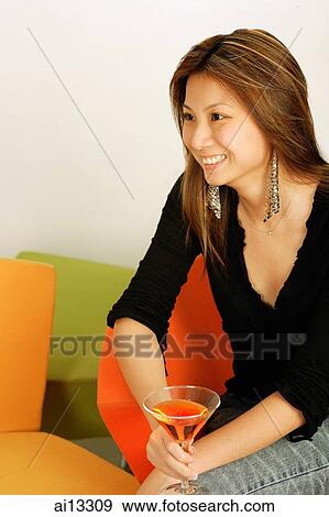 Young woman, sitting, holding drink, looking away View Large Photo Image Stock Photo - Young woman, sitting, holding drink, looking away. Fotosearch
