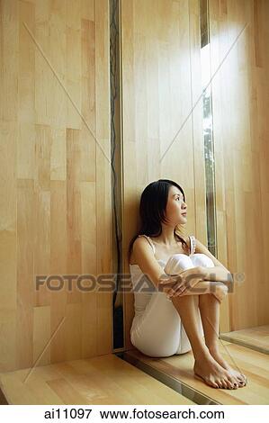 Young woman sitting, hugging knees, looking up View Large Photo Image Stock Photo - Young woman sitting, hugging knees, looking up. Fotosearch