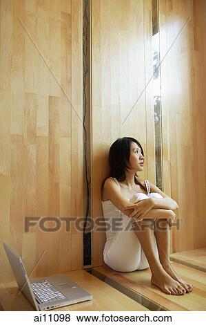 Young woman sitting, hugging knees, laptop next to her View Large Photo Image Stock Photo - Young woman sitting, hugging knees, laptop next to her. Fotosearch