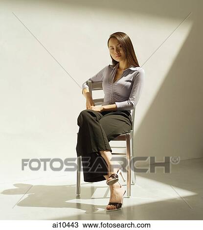 Young woman sitting on chair looking at camera View Large Photo Image Stock Image - Young woman sitting on chair looking at camera. Fotosearch