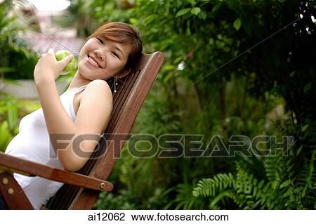 Young woman sitting on chair, outdoors. View Large Photo Image Stock Image - Young woman sitting on chair, outdoors.. Fotosearch