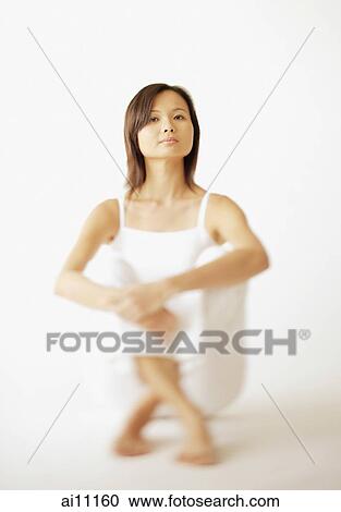 Young woman sitting on floor, looking at camera View Large Photo Image Stock Image - Young woman sitting on floor, looking at camera. Fotosearch