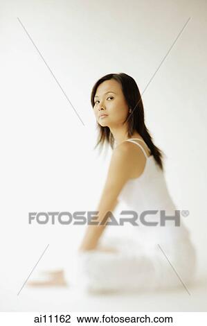 Young woman sitting on floor, looking at camera View Large Photo Image Stock Image - Young woman sitting on floor, looking at camera. Fotosearch