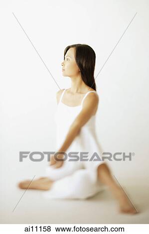 Stock Photo - Young woman sitting on floor, looking away. Fotosearch