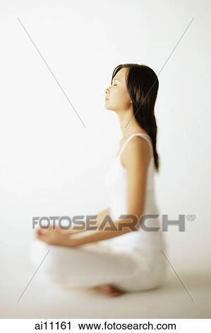 Stock Image - Young woman sitting on floor, profile. Fotosearch