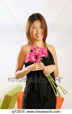 Picture - Young woman, smiling at camera, holding bouquet of flowers. Fotosearch