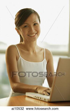 Young woman smiling at camera, laptop in front of her View Large Photo Image Stock Image - Young woman smiling at camera, laptop in front of her. Fotosearch