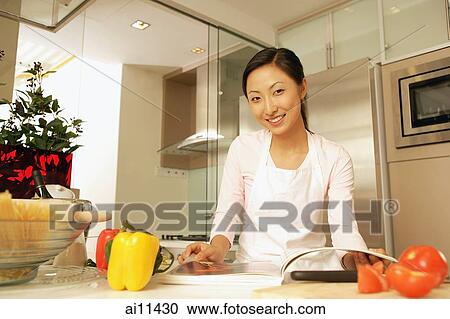 Young woman standing at kitchen counter, looking at camera. View Large Photo Image Stock Image - Young woman standing at kitchen counter, looking at camera.. Fotosearch