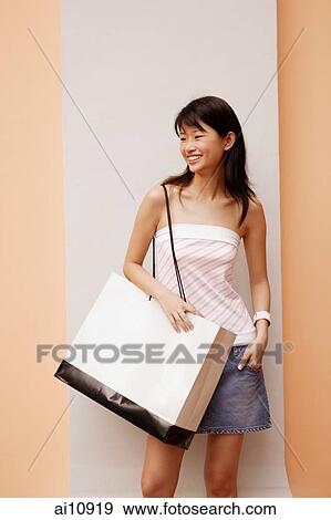 Young woman standing, carrying large shopping bag View Large Photo Image Stock Photo - Young woman standing, carrying large shopping bag. Fotosearch