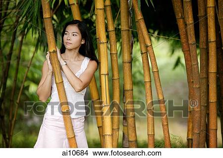 Picture - Young woman standing in a bamboo grove. Fotosearch