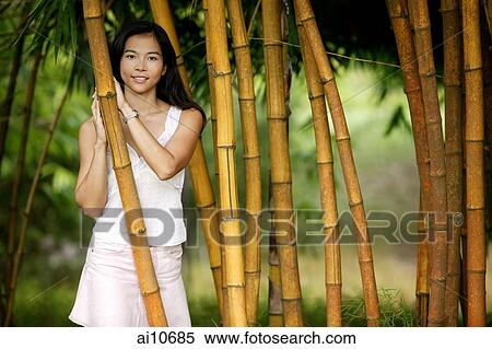 Young woman standing in a bamboo grove, smiling View Large Photo Image Stock Photography - Young woman standing in a bamboo grove, smiling. Fotosearch