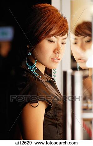 Stock Photo - Young woman standing, looking down. Fotosearch