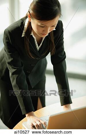 Young woman standing, using laptop View Large Photo Image Stock Photo - Young woman standing, using laptop. Fotosearch