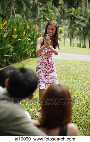 Young woman taking a picture of her friends View Large Photo Image Stock Image - Young woman taking a picture of her friends. Fotosearch