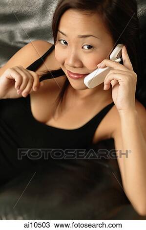 Young woman using a mobile phone, smiling View Large Photo Image Stock Image - Young woman using a mobile phone, smiling. Fotosearch
