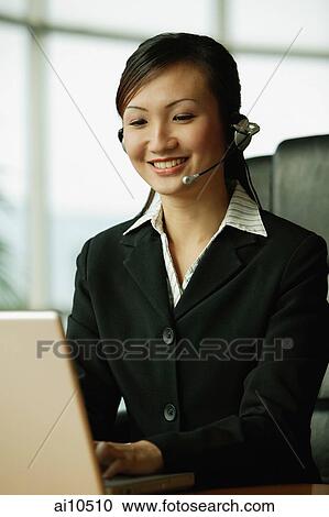 Young woman using laptop and wearing hands-free device View Large Photo Image Stock Image - Young woman using laptop and wearing hands-free device. Fotosearch