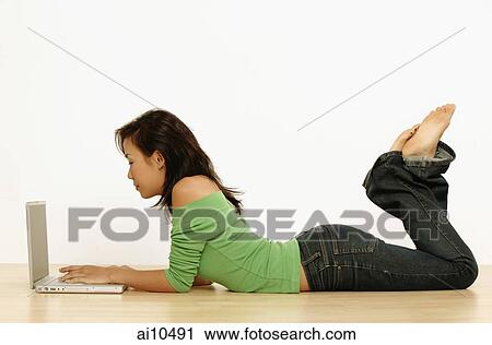 Young woman using laptop, lying on floor View Large Photo Image Stock Image - Young woman using laptop, lying on floor. Fotosearch