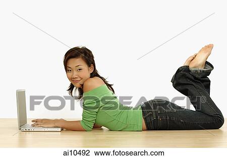 Young woman using laptop, lying on floor View Large Photo Image Stock Image - Young woman using laptop, lying on floor. Fotosearch