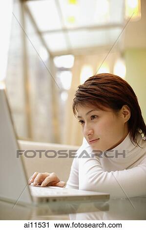 Stock Image - Young woman using laptop. Fotosearch