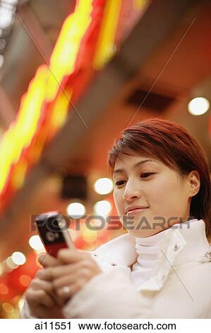 Young woman using mobile phone, looking down View Large Photo Image Stock Image - Young woman using mobile phone, looking down. Fotosearch