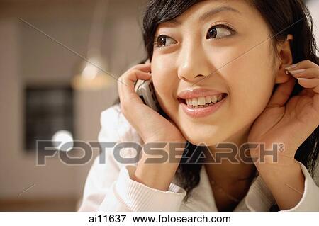 Young woman using mobile phone, touching ear and looking away View Large Photo Image Stock Photo - Young woman using mobile phone, touching ear and looking away. Fotosearch