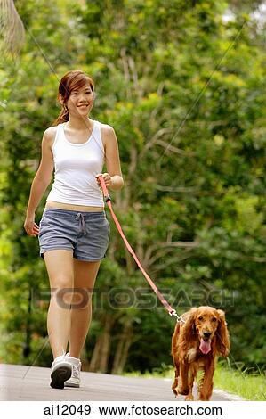 Stock Photo - Young woman walking her dog. Fotosearch