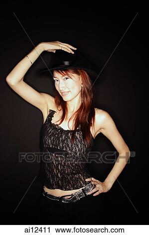 Stock Image - Young woman wearing cowboy hat, looking at camera. Fotosearch