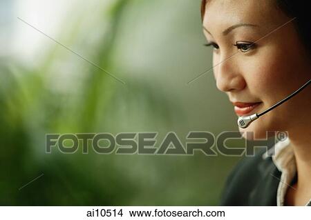 Young woman wearing hands-free device, looking down View Large Photo Image Picture - Young woman wearing hands-free device, looking down. Fotosearch