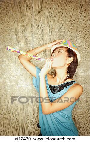 Young woman wearing hat, blowing noisemaker View Large Photo Image Stock Image - Young woman wearing hat, blowing noisemaker. Fotosearch
