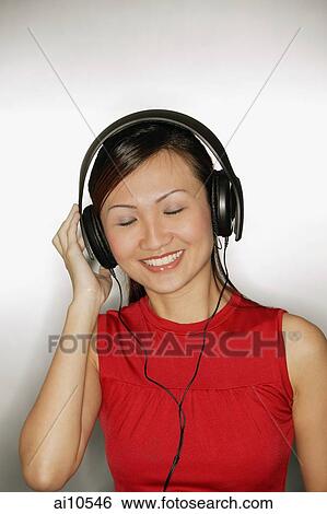 Young woman wearing headphones, smiling View Large Photo Image Stock Photograph - Young woman wearing headphones, smiling. Fotosearch