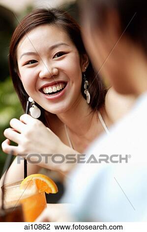 Stock Image - Young woman with a drink, smiling. Fotosearch
