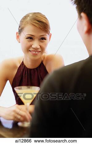 Young woman with cocktail glass, man facing her View Large Photo Image Stock Photograph - Young woman with cocktail glass, man facing her. Fotosearch
