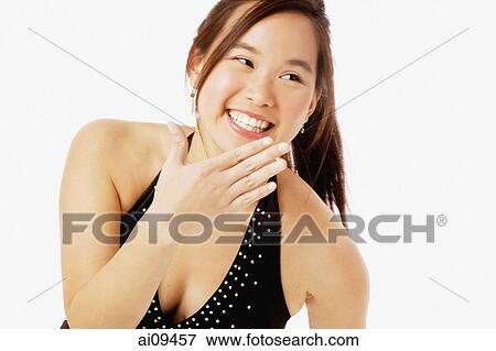 Stock Photo - Young woman with hand on chin, smiling.. Fotosearch