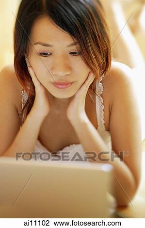 Young woman with hands on face, looking at laptop View Large Photo Image Stock Image - Young woman with hands on face, looking at laptop. Fotosearch